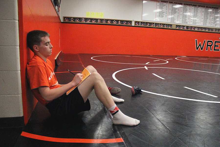 Before wrestling practice, Daniel Woods (10) rewrites the five goals he chose at the beginning of the season.