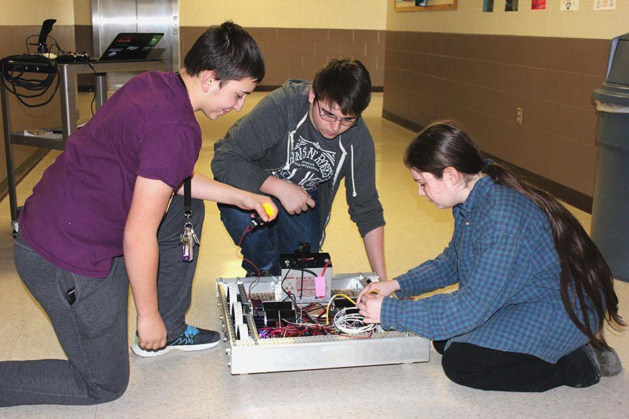 Ethan Goodwin (10), Colby Samuelson (9), and Taylor Cherry (11) work on the robot during one of the many practice sessions.