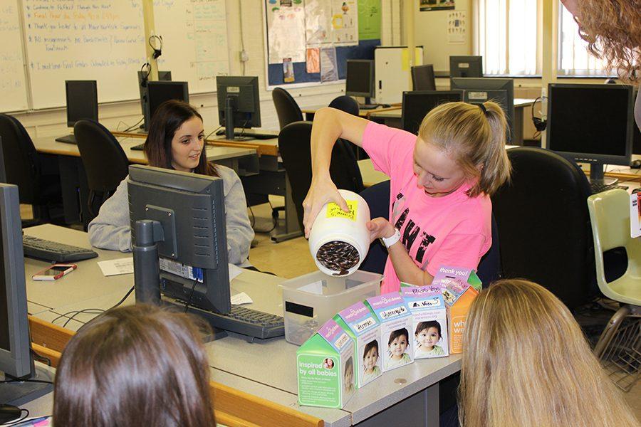 FBLA members Hayley Schaul and Meghan Hoefer pour coins into a container to be counted. 