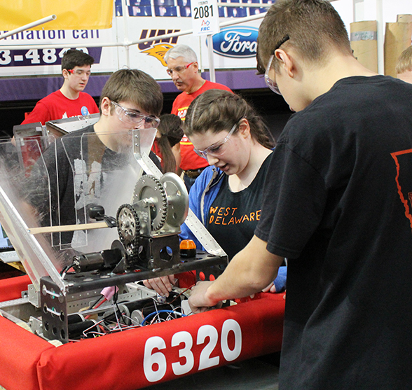 Colby Samuelson (9), Taylor Cherry (11) and Tyler Salow (10) examine the robot before competition.
