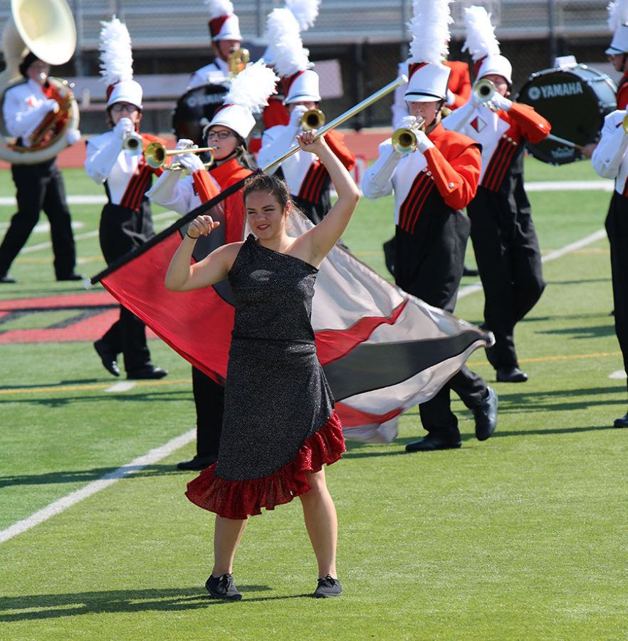 Color guard member Gabrielle Schuman (10) waves around her flag with a smile on her face.