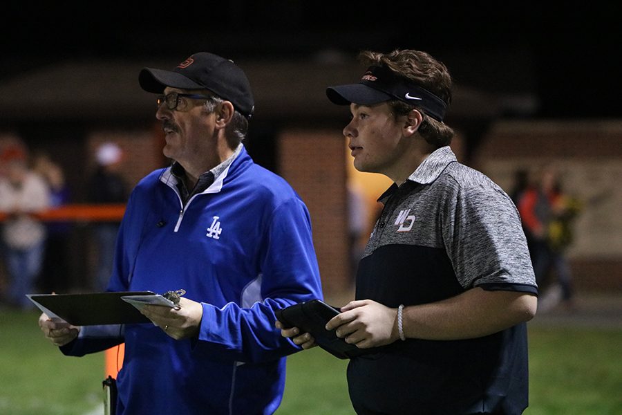 BIll Logan, sideline reporter, and Dylan Linderwell (12) watch closely as the athletes make their play.