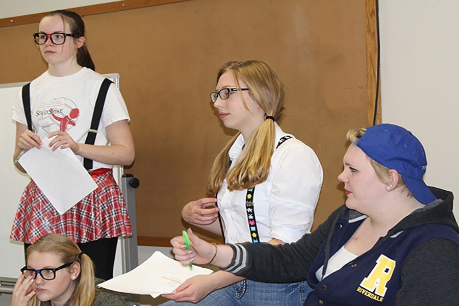 Freshmen Morgan Collier, Brooke Holtz and Mikaila Neuzil portray geeks that are frightened by Brynn Boeckenstedt’s jock persona during their choral reading practice.
