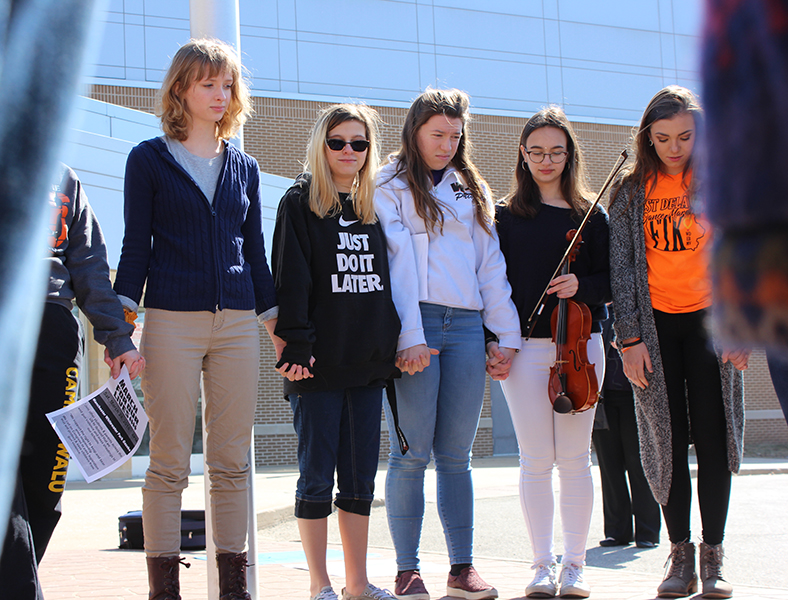 Holding hands, students stand in silence around the names of the victims. From left: Emily La Rosa (12), Lila Sage (9), Olivia Neuzil (11), Laia López Rigol (11), Aleah Vaske (12).