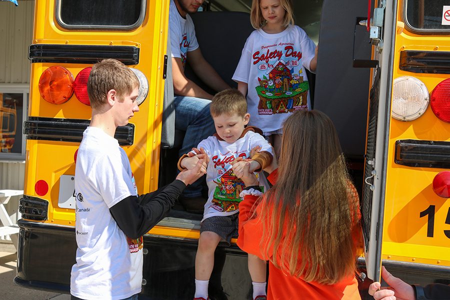 Zach Goebel (10) and Alexis Hartman (9) safely help students off the bus after learning about bus safety. 