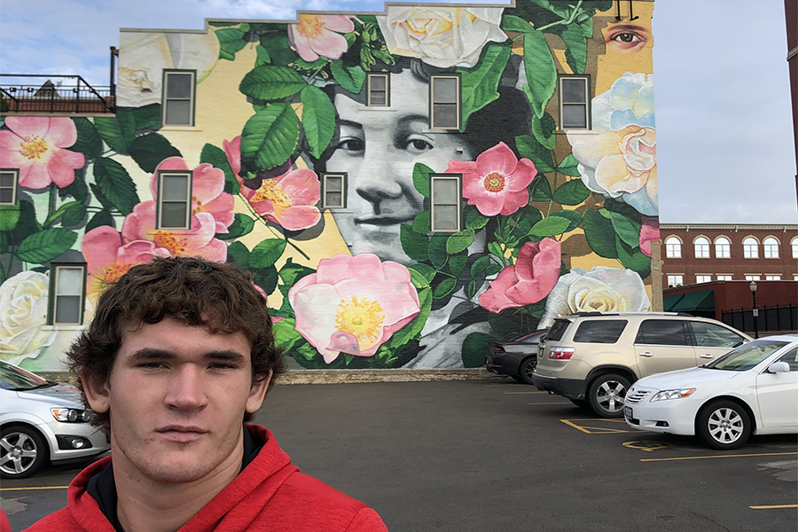 Junior Jack Neuhaus poses in front of a mural on their art trip. 