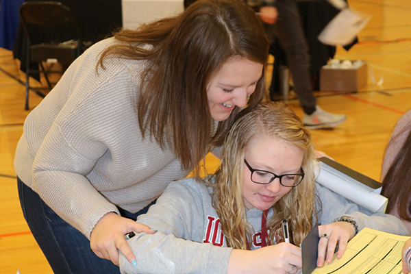 While at the charity and contributions table, seniors Claire Rausch and Lauren Ryan fill out a check.