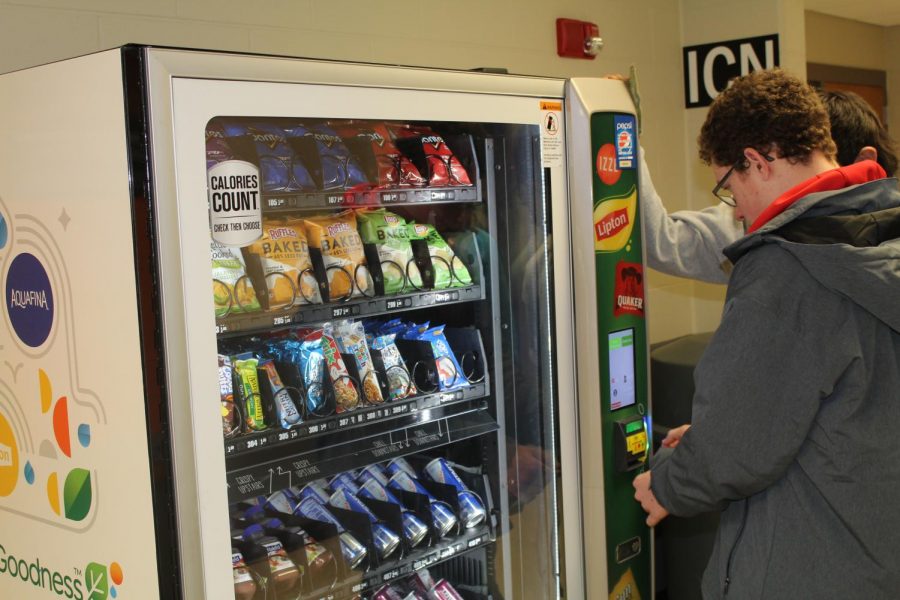 Using the new vending machine, sophomore Carter Peyton inserts a dollar to purchase a healthy snack. 