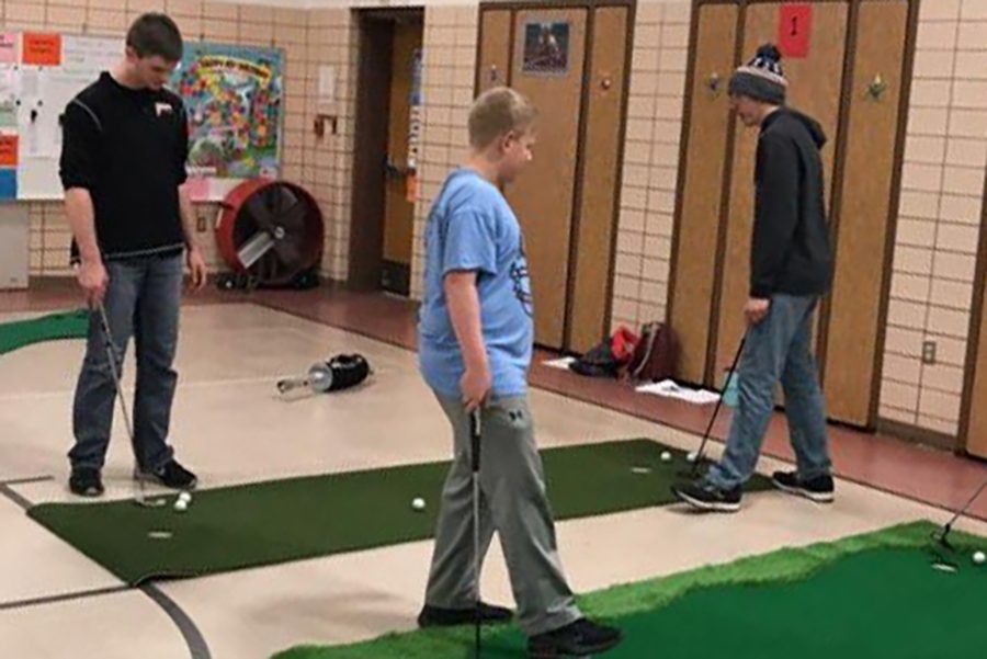 Tyler Langel (12), Brandon Larson (11), and Trevor Soppe (9) practice their putting skills on the indoor putting greens. 