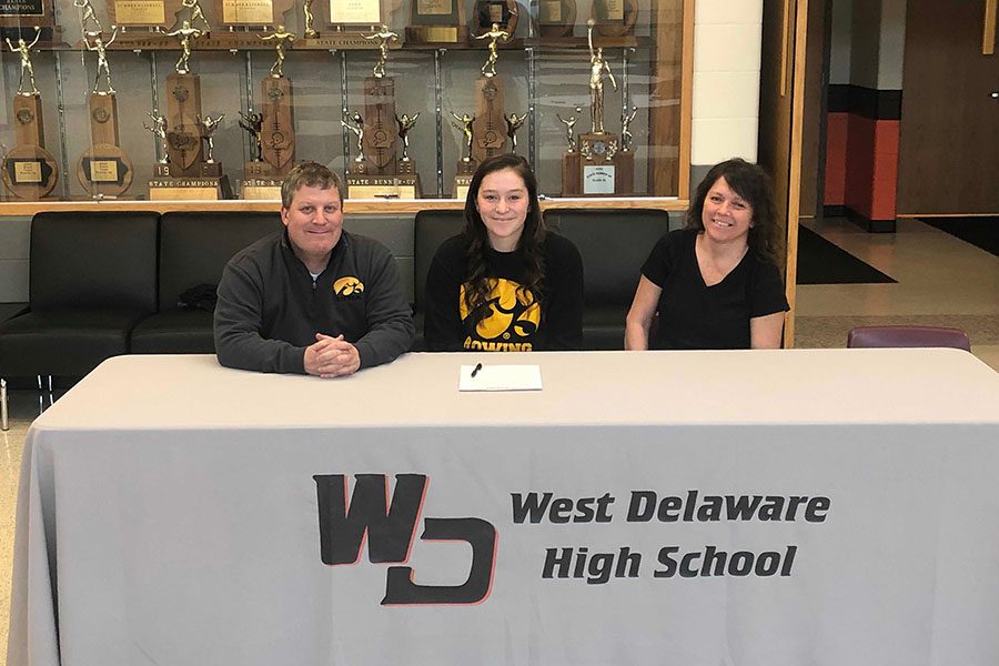 Lilly Meyer (12), with her parents by her side, signs for the University of Iowa Rowing team.  