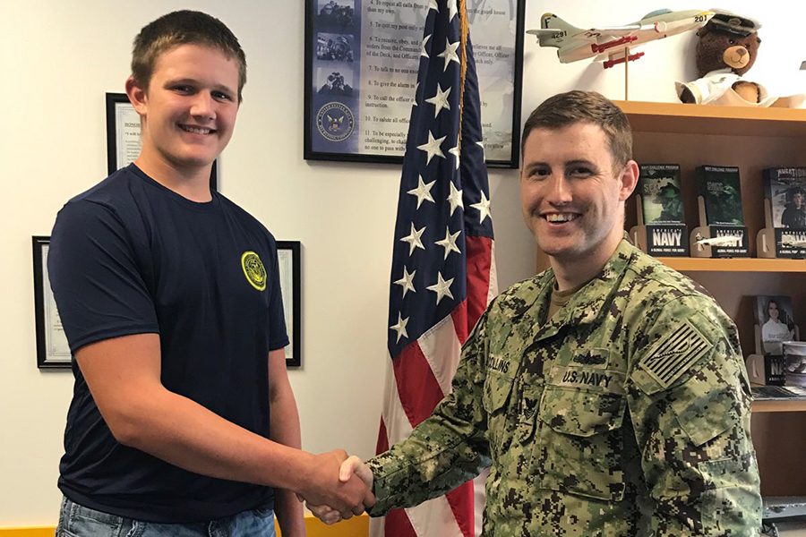 Elijah Heims (12) shakes hands with James Collins, his Navy Recruiter, on Sept. 10 after signing into the Navy.