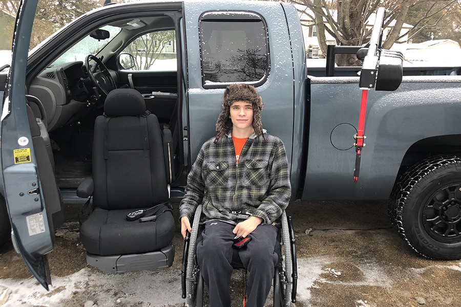 Posing with his new truck, Zach Fisher (12) shows the handicap accessible seat and wheelchair lift outside of the truck.