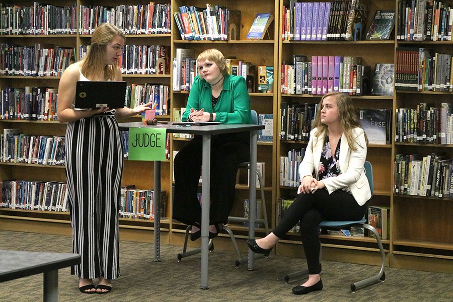 Taylor Hammer (11) questions Molly Mullis (11) on her involvement as Reverend Hale in the Advanced English III Mock Trial while Brynn Boeckenstedt (11) keeps order as the judge.