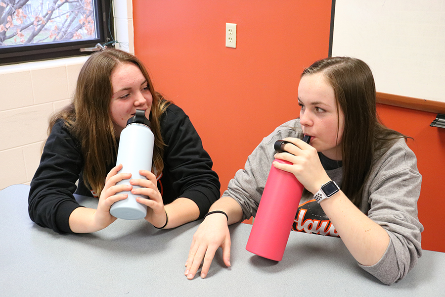 Mia Peyton (11) and Morgan Collier (11) take a sip from their own water bottles during class.