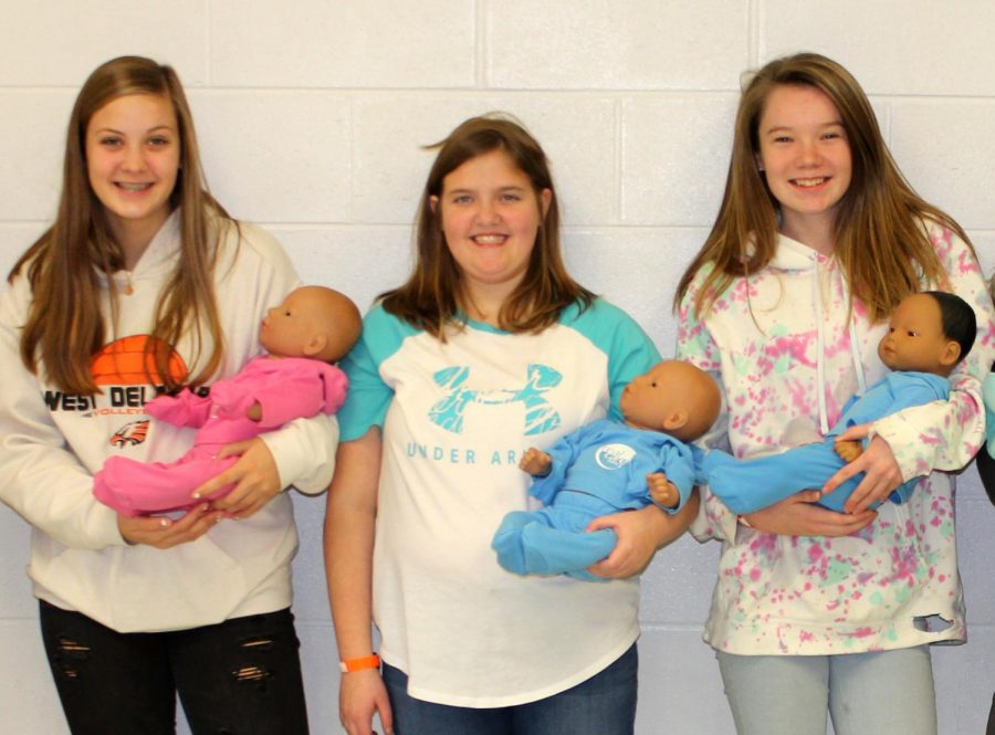 Students Aleah Winkowitsch (10), Delaney Holz (9), Victoria Boeckenstedt (9) pose before preparing to bring home their RealCare Baby. 