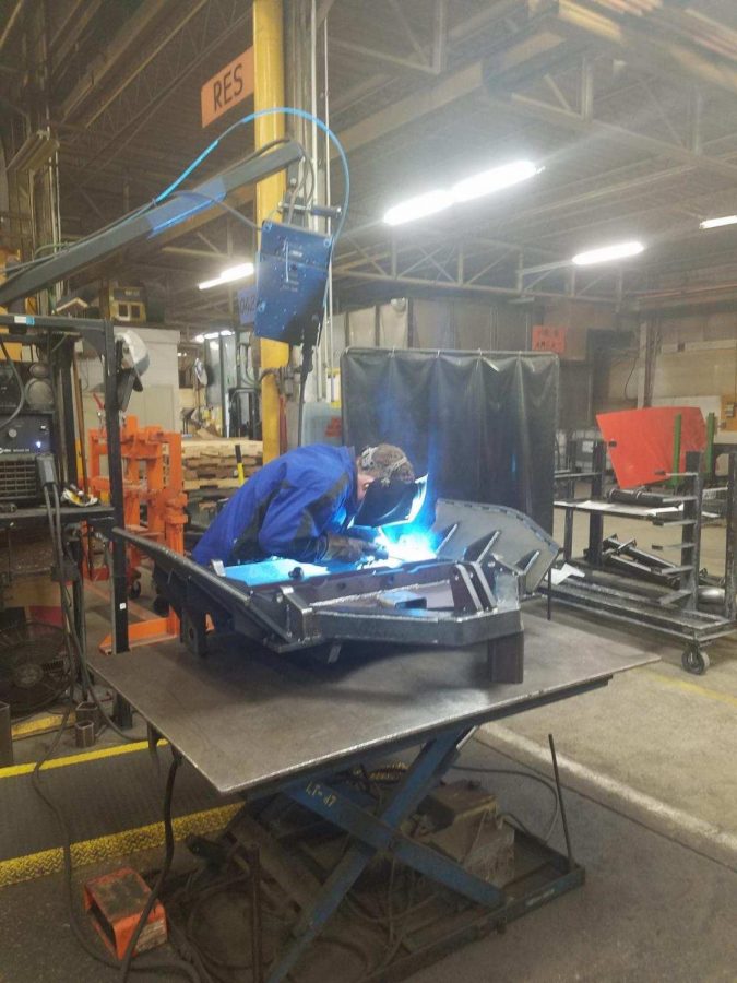 Carter Peyton (11) welds  Dump body parts together in his department.