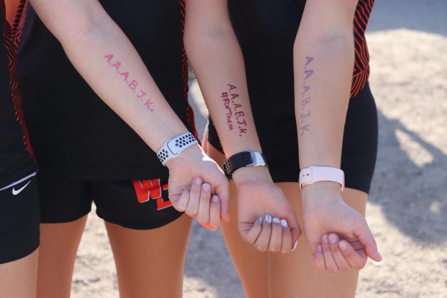 Honoring their quarantined teammates, the girls cross country team writes the initials of four seniors, one junior and one freshman who was quarantined due to exposure to COVID-19 on Oct. 6, at their only home meet of the season.
