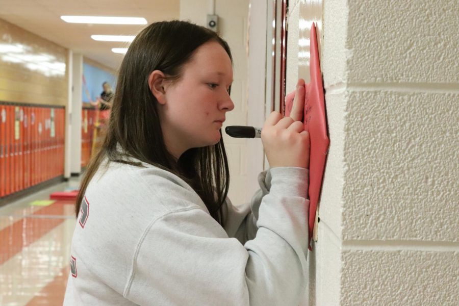While decorating the juniors’ hallway for homecoming week, Lydia Heims (11) writes on a directional arrow for their theme ‘Game of Life’. Juniors won the 2021 Hallway Decoration contest.  