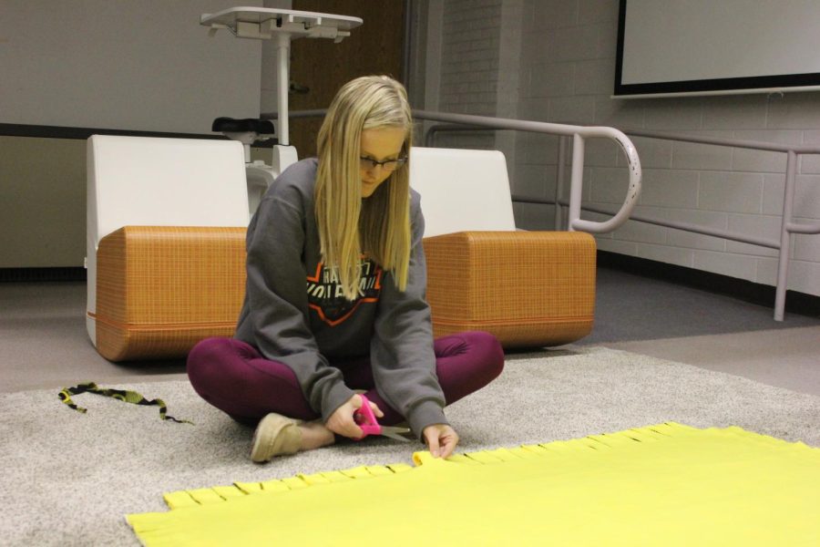 Allie Demmer works on cutting the tabs to make the tie blanket. 