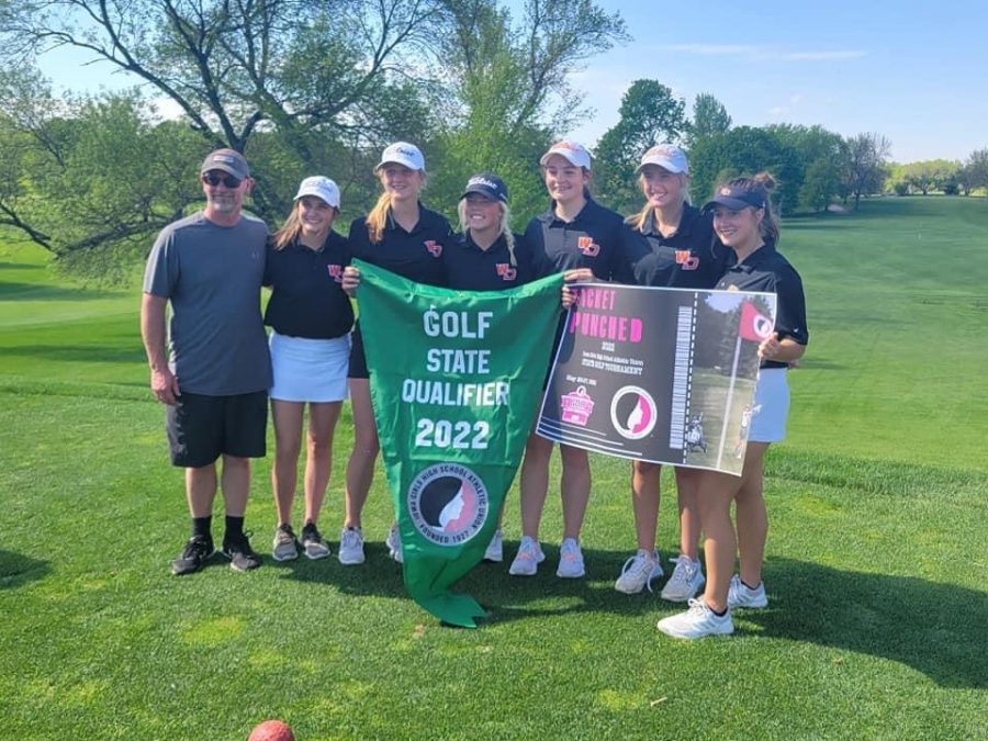 The girls golf team poses with their banner after placing second at their regional tournament: Coach Brett Mather, Emma Hogan (10), Susie Funke (9), Ella Koloc (12), Andrea Wubbena (9), Kennedy Klostermann (11), Maylin Coates (10).