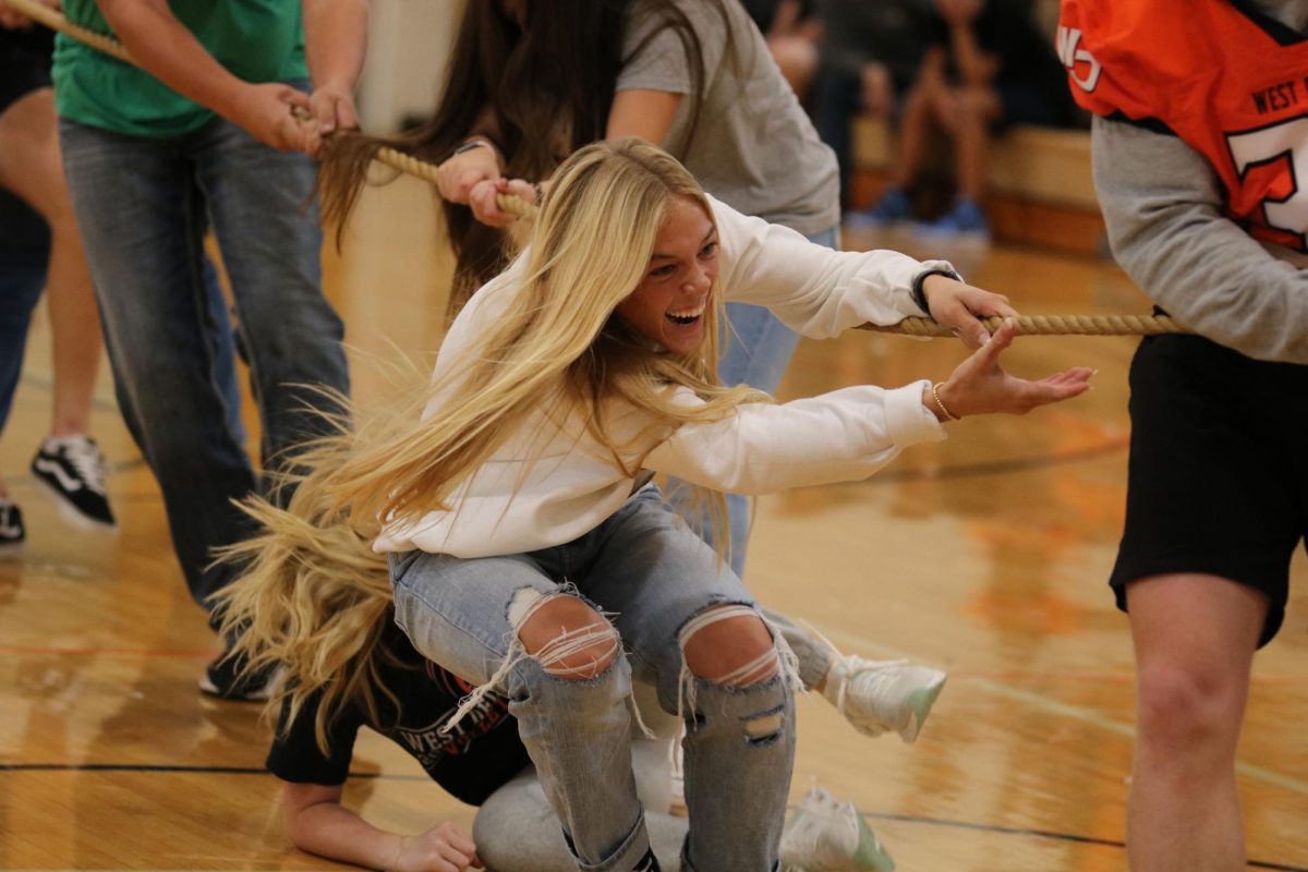 Struggling to win the battle, sophomore Norah Peyton helps her team during the tug-of-war competition at the homecoming pep rally on Sept. 22. The sophomore team lost to the juniors, who went on to win overall.