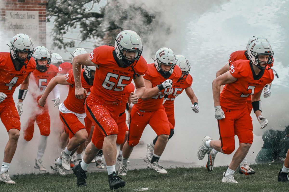 Prior to kickoff, senior Noah Felton leads the charge through the smoke. The Hawks defeated Independence, 29-21, on a cold and rainy senior night.
