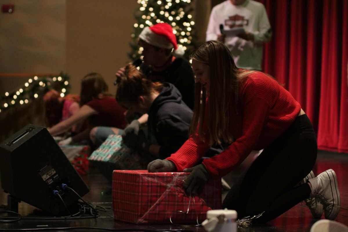 While racing against others, senior Ashleigh Hartman attempts to unwrap a present while wearing gloves.