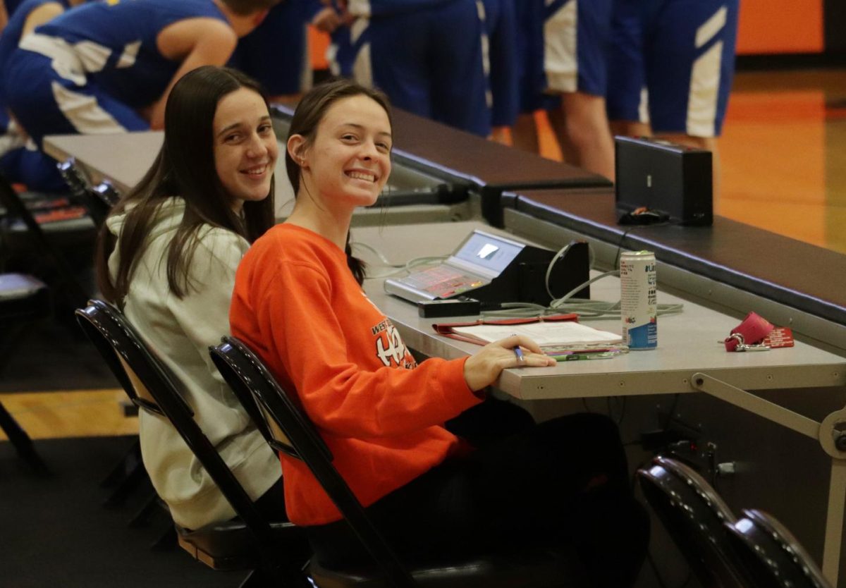 Kate Loecke (12) and Stephanie La Rosa (12) pose for a picture during a timeout. Both Loecke and La Rosa have been the stat takers for the boys basketball home games for the past four years.