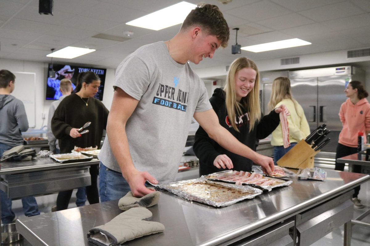 FFA members Jack Smith (12) and Chloe Peyton (12) prepare bacon for the FFA Staff Breakfast. Students in FFA hosted a breakfast for all the staff members in West Delaware High School. (Photo By Helen Temeyer) 