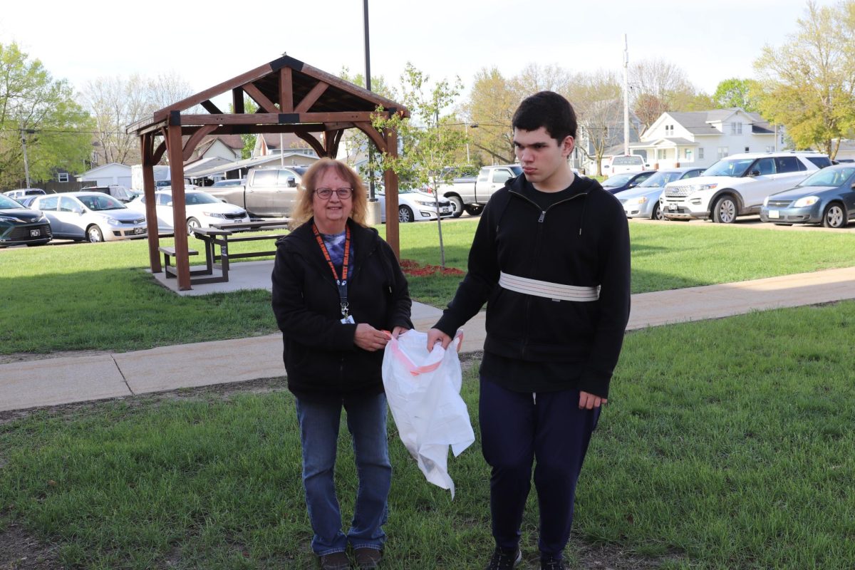 On senior service day, associate Pamela Schaffer and senior Cole Christensen walk around the school grounds and pick up trash. 