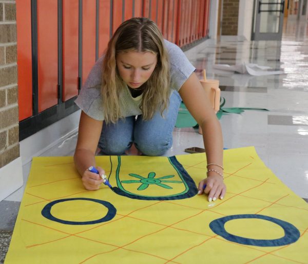 Preparing for homecoming week, senior Josie McMahon draws SpongeBob's house for the senior SpongeBob hallway theme. McMahon covered the white walls with colorful and bright posters. 