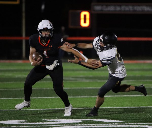 While running the ball, quarterback Brent Yonkovic (12) pushes away his opponent. The team beat CPU, 49-6.