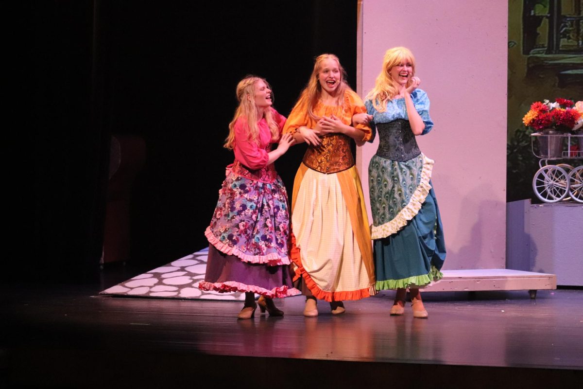 Acting as Les Filles De La Ville, Ali Robinsion, Emma Millenkamp. and Alania Bardgett fan over Gaston. 