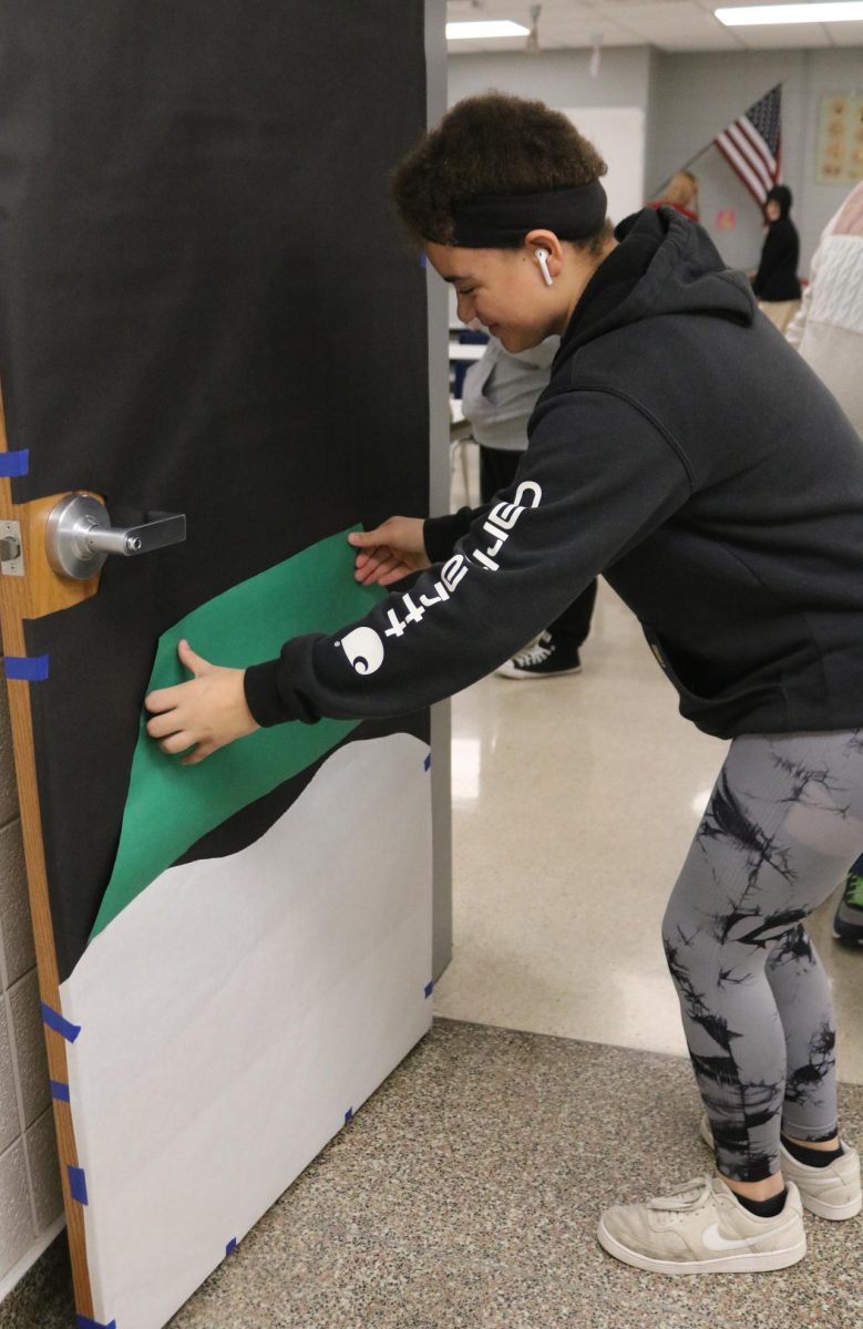 Helping out her homeroom, freshman Natalie Weber tapes up the bottom of a Christmas tree.