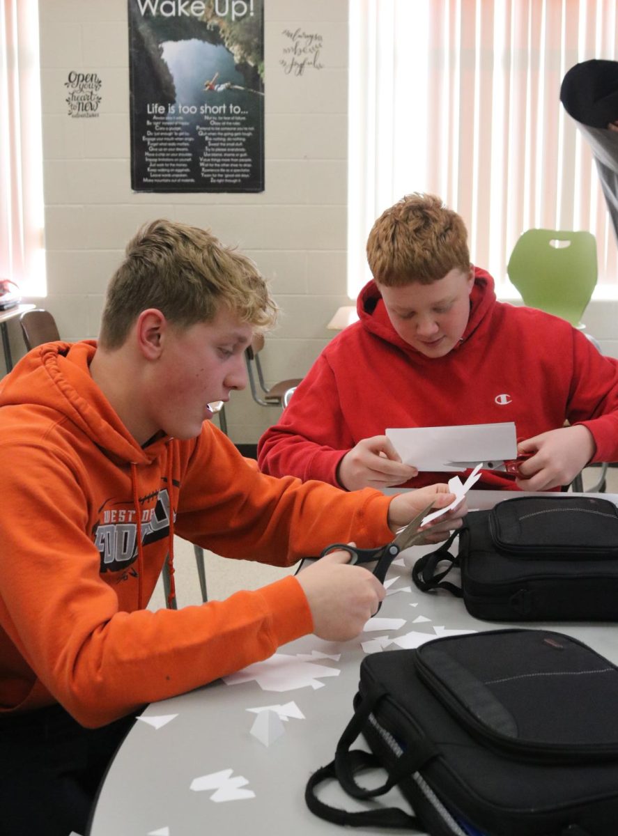 Freshmen Wyatt Mensen and Max McDowell cut paper snowflakes to add to their snowy door. 