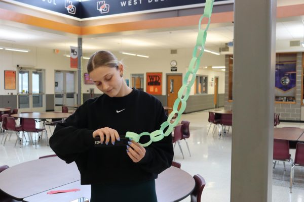 Stapling the kindness links together, senior Susie Funke helps out student council by adding to the juniors' kindness chain. 