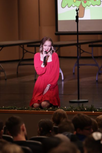 Senior Emily Gudenkauf singing Santa Baby at the holiday assembly.