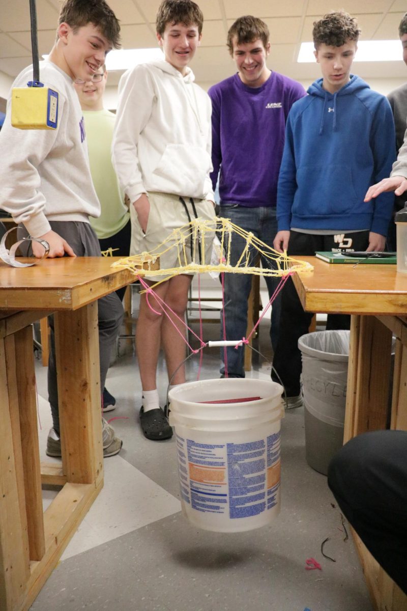 Waiting with anticipation, Lane Gudenkauf (9), Reid Bockenstedt (9), Wes Devaney (12), and Harrison Nefzger (9) watch as the bridge holds the weight of five books. 