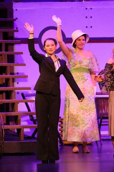 Addisyn Kintzle (10) waves to the audience during the opening number "Bon Voyage."