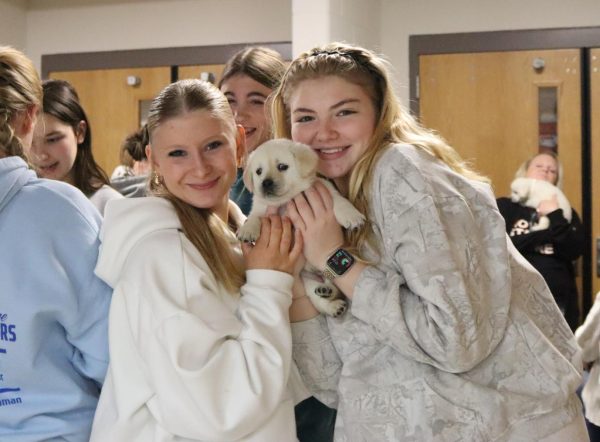 Seniors Natalie Beilby and Maya Pennington pose with their puppy.