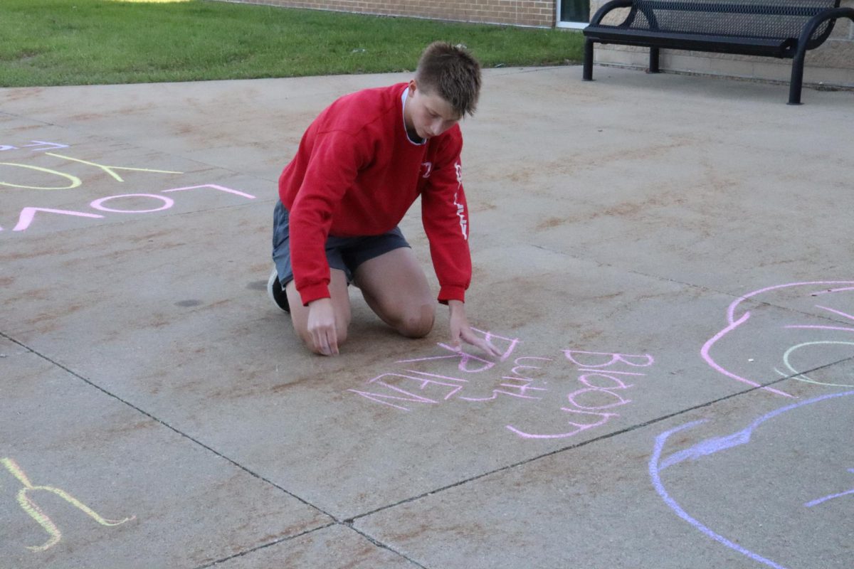 Ryan Jolley (9) writes Bloom with Friends on the side walk with chalk.