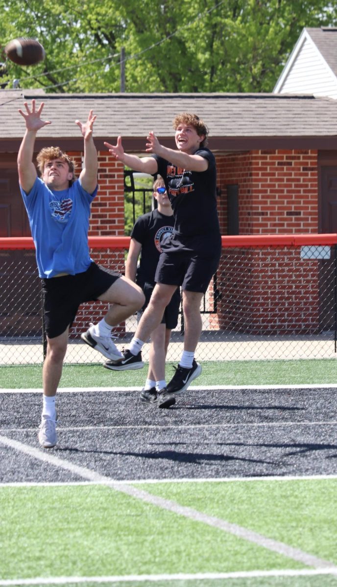 Jaxson Meyer (11) and Wyatt Johnson (11) leap to catch a football after eating burgers grilled by the pork producers.