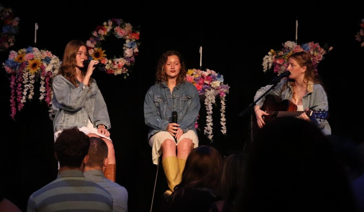 On stage, Alaina Bardgett (12), Grace Sleper (12), and Makayla Seeley (11) sing “Leaving on a Jet Plane” by John Denver for the dinner show.

