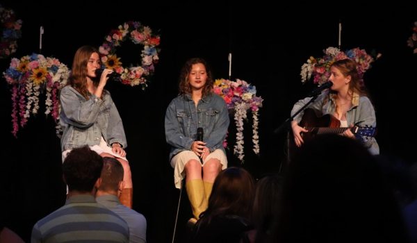 On stage, Alaina Bardgett (12), Grace Sleper (12), and Makayla Seeley (11) sing “Leaving on a Jet Plane” by John Denver for the dinner show.