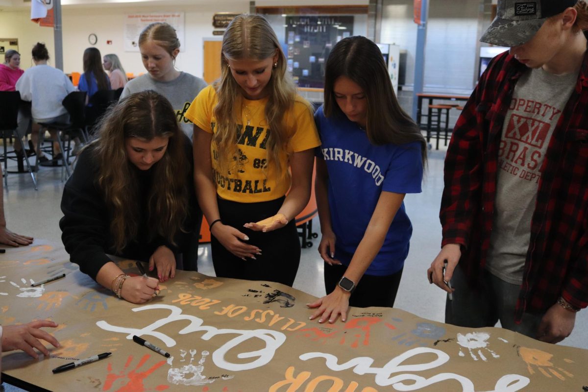 Standing together, Maggie Lyness (12), Natalie Beilby (12), Vedah Langel (12) and Logan Bemer (12) sign under their handprint.
